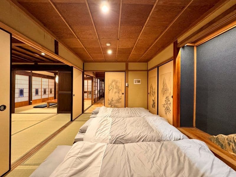 Futons laid out in a tatami room beneath hanging scrolls