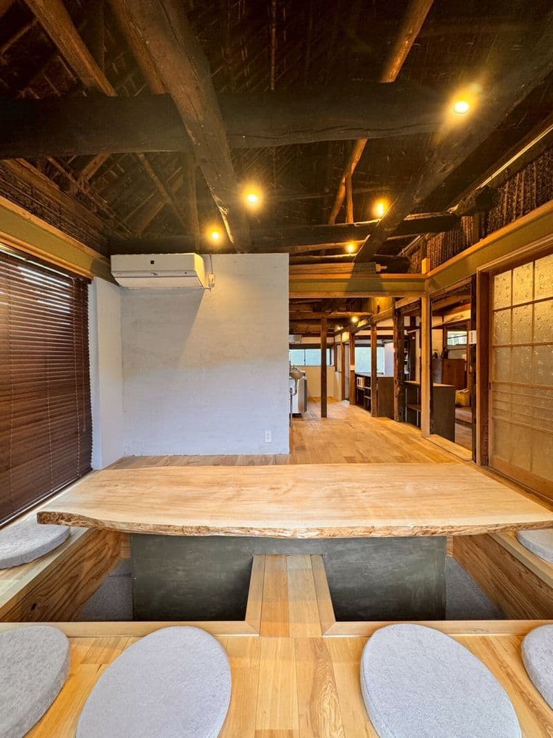 A live-edge dining table with sunken seating, kitchen beyond