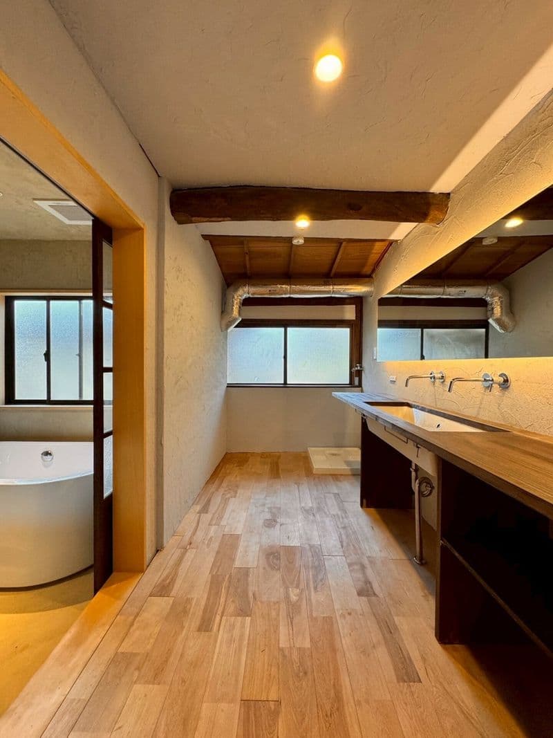 A washbasin with two faucets, the bathroom visible beyond