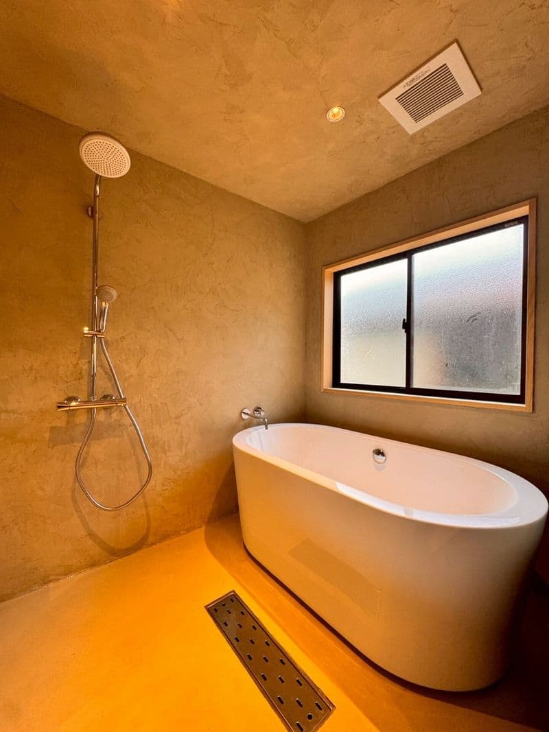 The bathroom with a rain shower and a freestanding tub