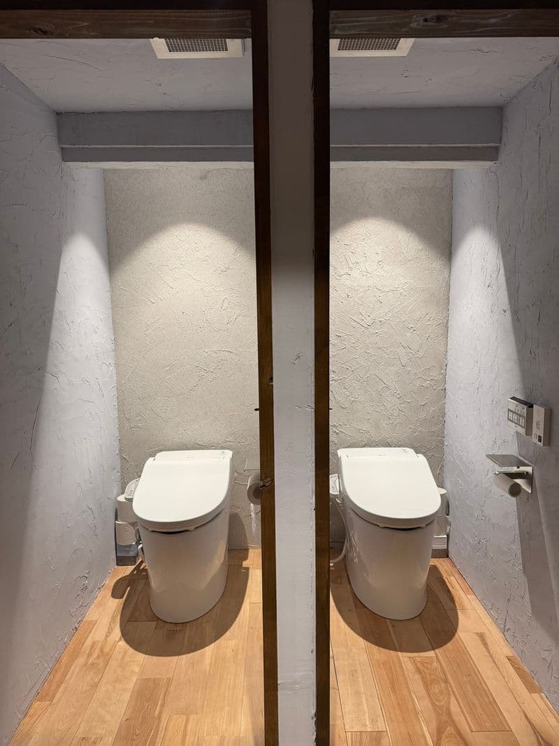 Two toilets in separate rooms, side by side