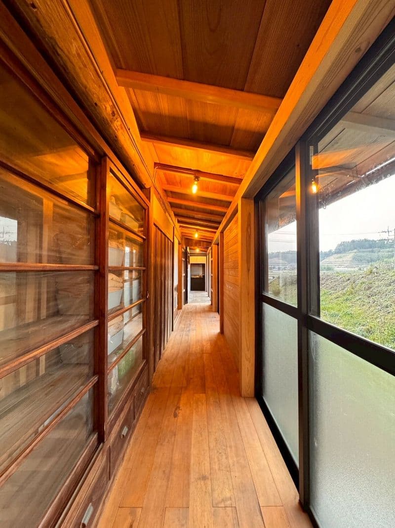 A wooden corridor with fields visible through the glass doors
