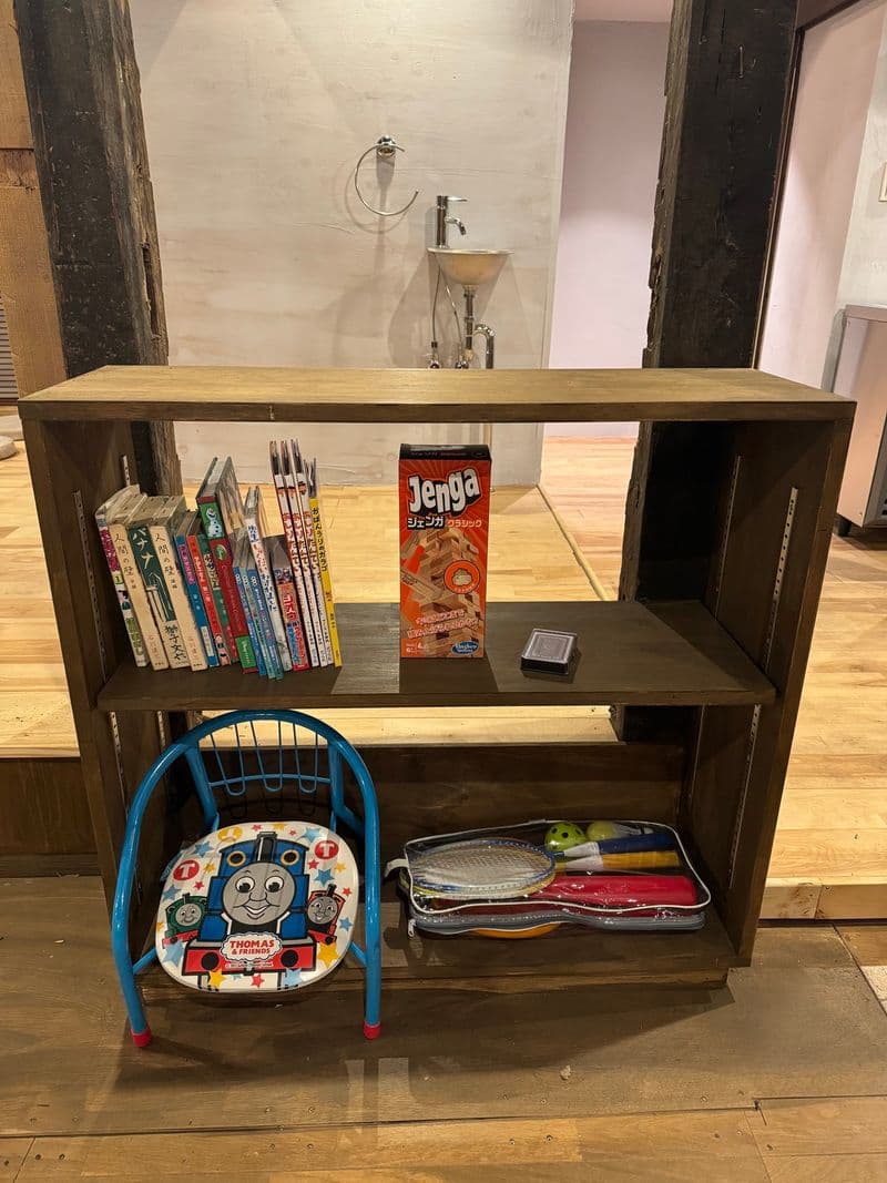 A shelf holding picture books, Jenga and badminton rackets