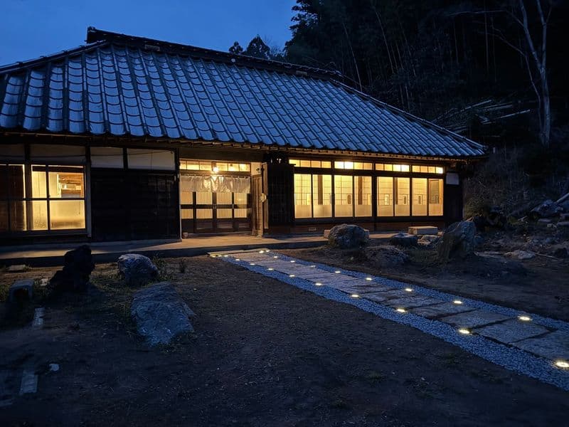The main house at night, with lights along the stone path