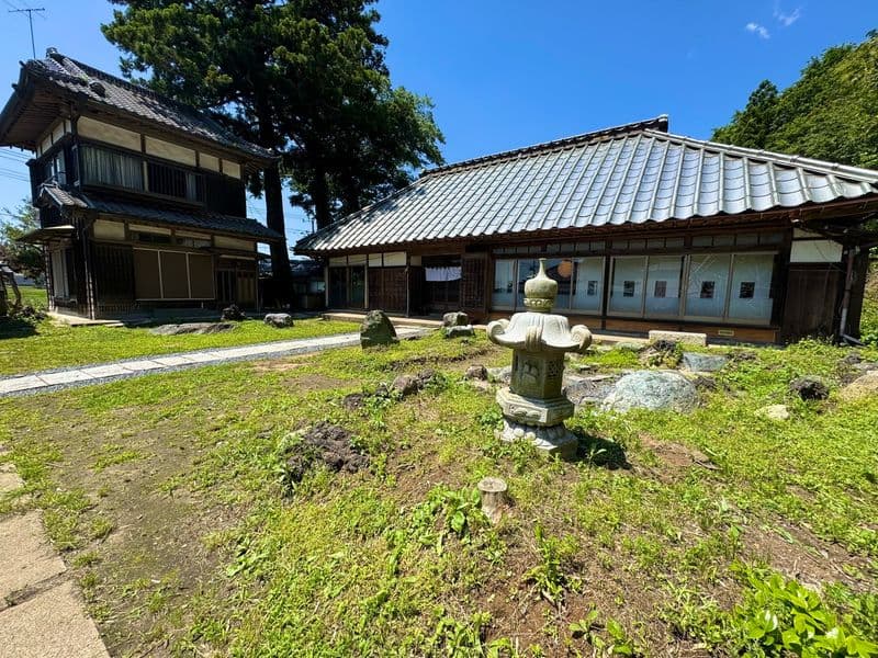 The grounds on a clear day: the house, a stone lantern and a neighboring building