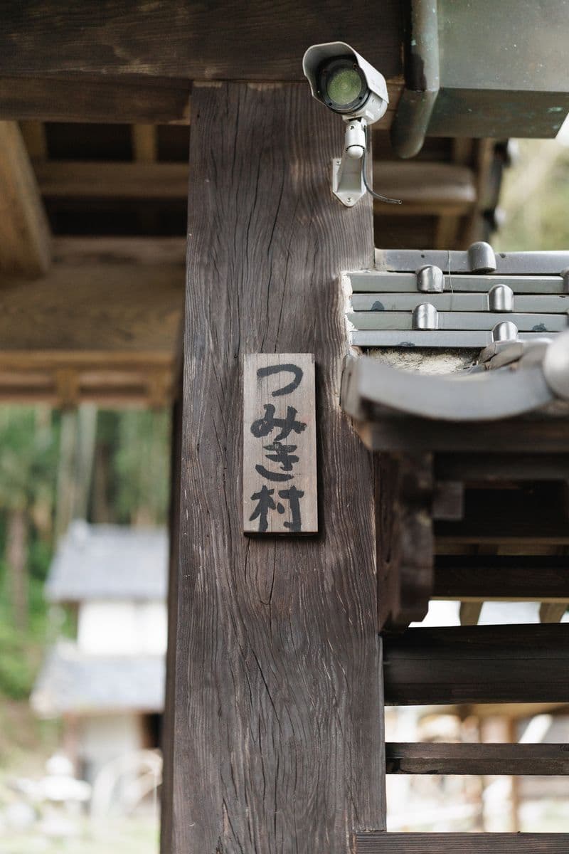 A wooden sign reading “Tsumiki Mura” on the gate post