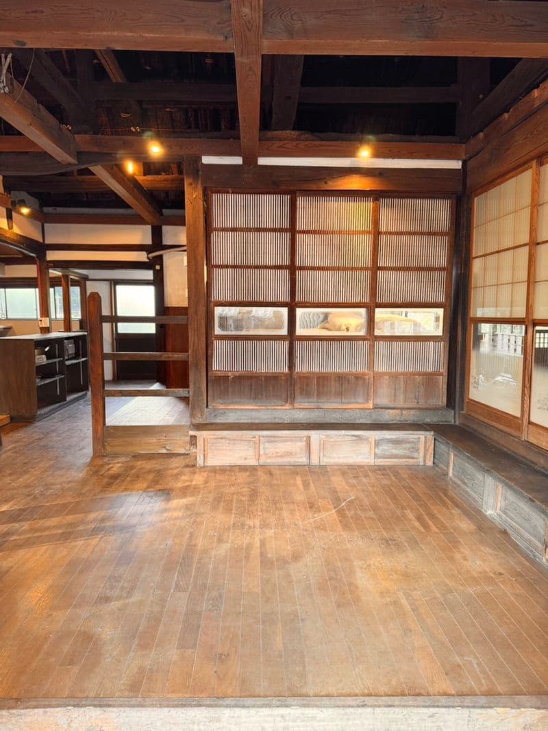 A wide wooden-floored room framed by heavy beams and lattice doors