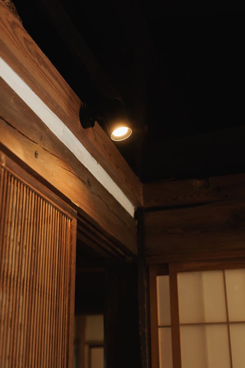 A spotlight mounted on a beam beside a shoji screen
